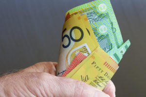 A man's fist full of Australian dollar notes.