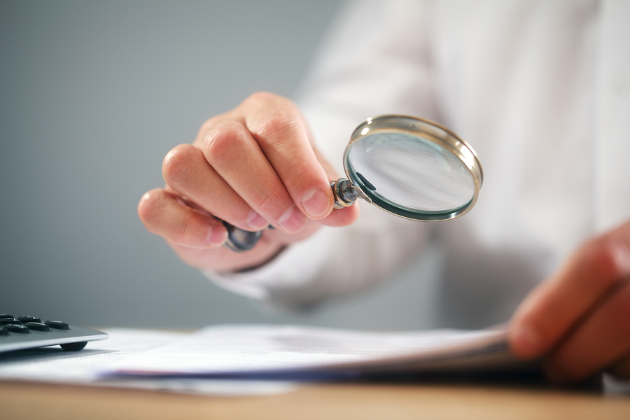 Businessman reading documents with magnifying glass concept for